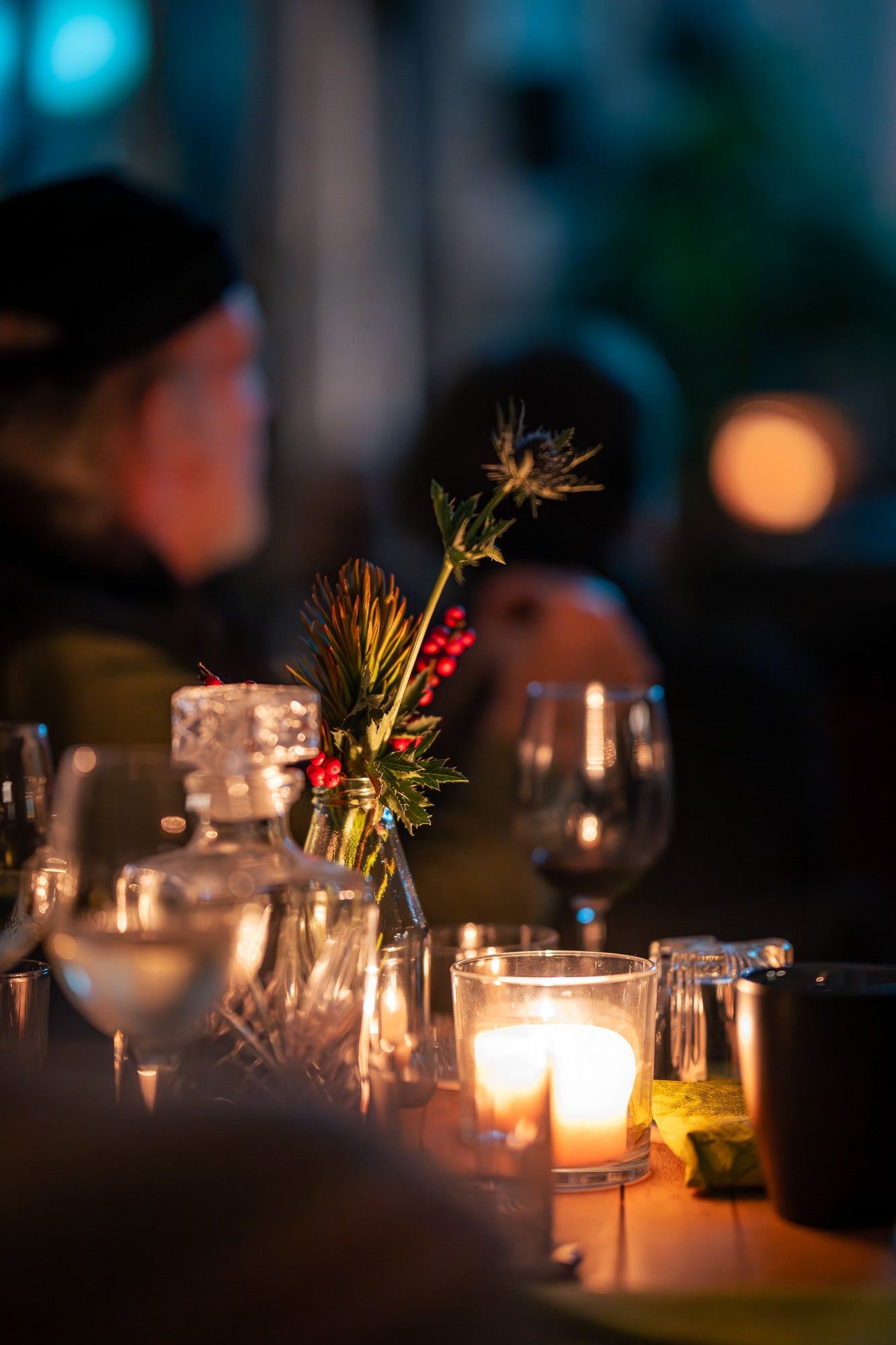 Tischdeko, Kerzen, Menschen im Hintergrund. Grundsätzlich ein dunkles Bild. Romantischer Flair. 
Bildrecht bei Thomas Mohn.