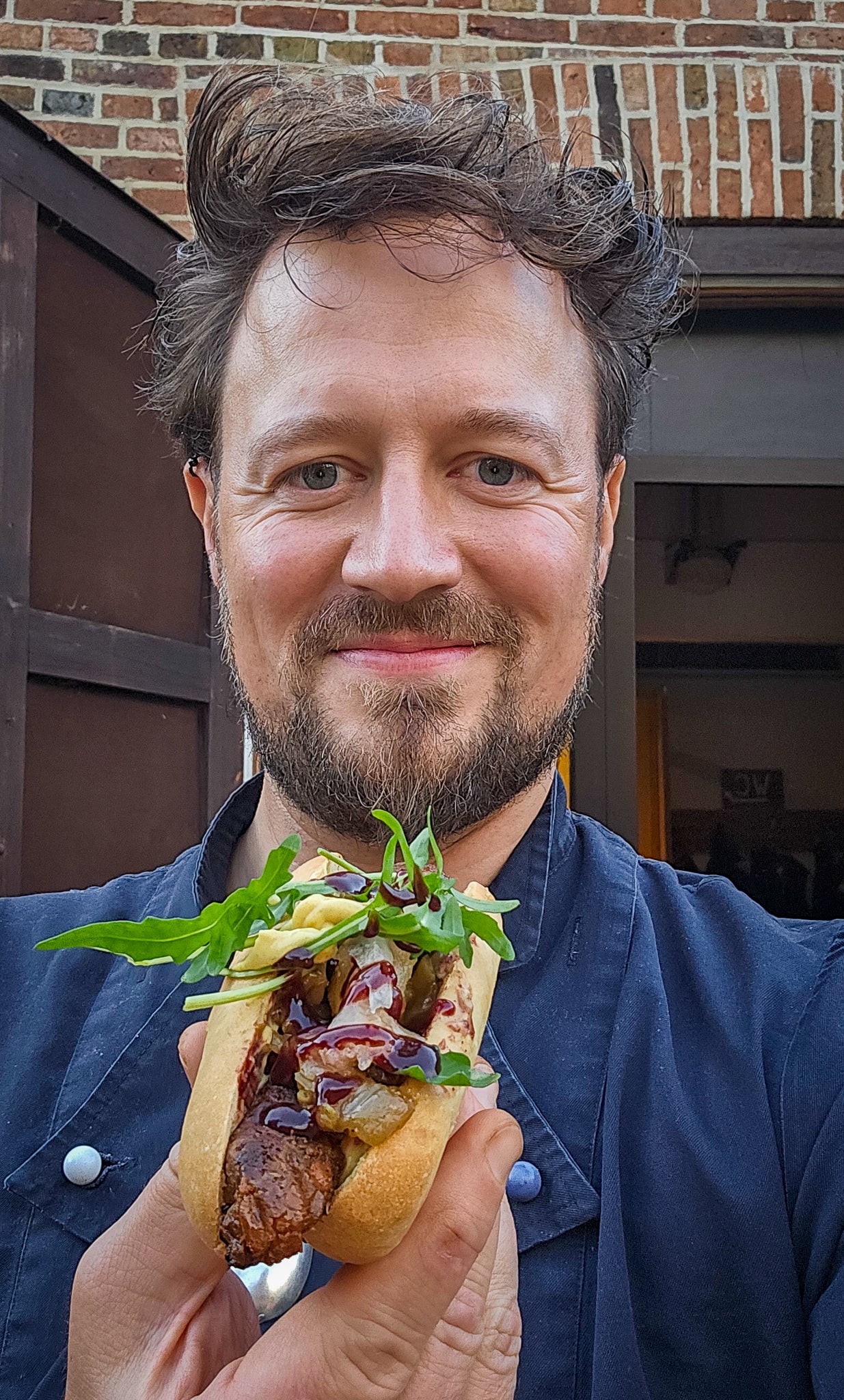Elias mit selbstgebackenem, veganem Hot-Dog vor der E.ssenz