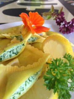 Aufgeschnittene Ravioli mit weiß-grüner Füllung und garnierten Blüten